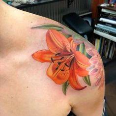 an orange flower on the back of a woman's shoulder