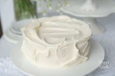 a white frosted cake sitting on top of a plate next to two plates with flowers