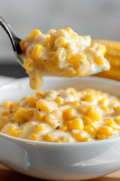 a spoon full of macaroni and cheese with corn on the cob