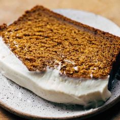 a piece of cake on a plate with cream cheese frosting and a black fork