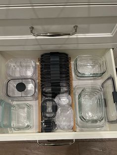 an organized drawer with glass containers and lids