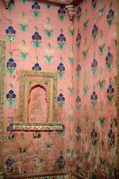 an old room with pink and green wallpaper, blue flowers and a mirror on the wall