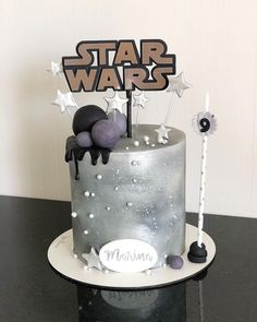 a star wars themed cake on a black table with white stars and silver frosting