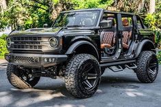 a black jeep with brown leather seats is parked on the street in front of some trees