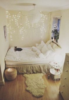 a cat laying on top of a white bed in a room with wooden flooring