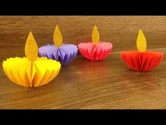 three colorful paper candles sitting on top of a wooden table