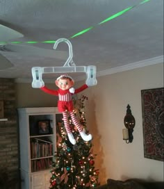 a christmas tree with an elf hanging from it's top and lights on the bottom