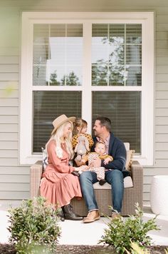 a man and woman sitting on a couch with two children in front of a window