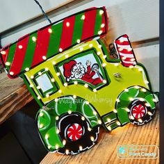 a green and red christmas train with lights on it's sides sitting on a wooden table