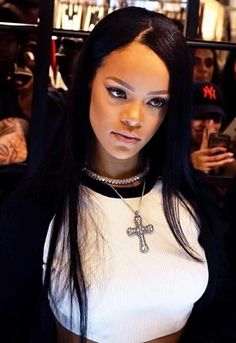 a woman with long black hair wearing a cross necklace