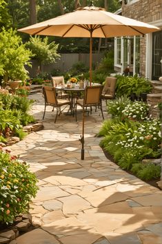 an outdoor dining area with patio furniture and umbrella over the table, surrounded by greenery