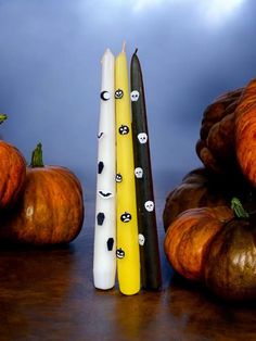 three candles with faces on them sitting next to pumpkins