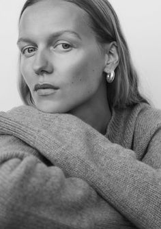 a black and white photo of a woman with her arms wrapped around her neck looking at the camera