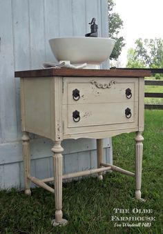 an old dresser with a sink on top in front of a barn door and grass