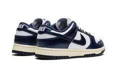 The Women’s Nike Dunk Low PRM "Vintage Navy" is a women’s-exclusive colorway of the retro basketball shoe with a vintage-inspired design.  The “Vintage Navy” honors the Dunk’s storied history as a mid-1980s college basketball team shoe with its aged, vintage look.  The cream rubber midsole mimics the oxidation process rubber undergoes after years of use.  Up top, the shoe features a white leather base with Vintage Navy leather overlays and Swoosh branding that have a slight sheen and textured fi Retro Basketball Shoes, Retro Basketball, Basketball Team, Navy Shoes, Navy Leather, College Basketball, Basketball Teams, The Cream, Nike Dunk Low