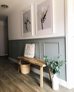 a wooden bench sitting in front of two pictures on the wall next to a plant