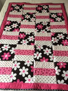 a black and white quilt with pink flowers on it