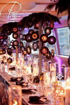 a long table with many candles and plates on it, along with palm tree centerpieces