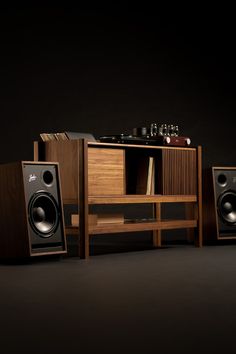 two speakers and a record player in front of a cabinet