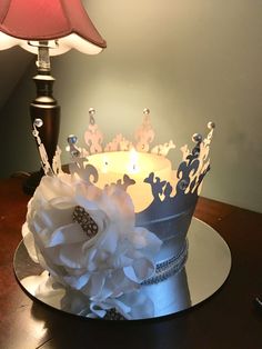 a cake with a crown on it sitting on top of a table next to a lamp