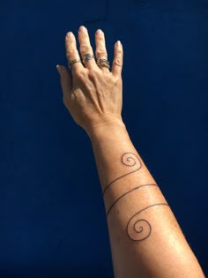 a woman's hand with three spiral tattoos on it