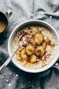 a bowl of oatmeal with bananas and chocolate on top, next to a cup of coffee