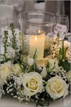 white flowers and greenery are arranged on a table