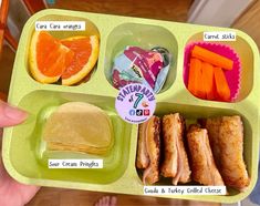 a child's hand holding a green tray with food in it and labels on the side