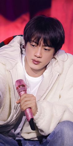 a young man holding a microphone while sitting on a red chair with his eyes closed