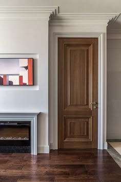 an empty living room with wood floors and a painting hanging on the wall next to a fireplace