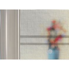 a blurry image of a vase with flowers in it is seen through a screen door