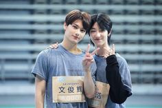 two young men standing next to each other giving the peace sign