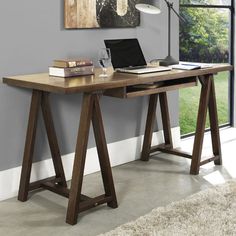 a wooden desk with a laptop on it in front of a window and a rug