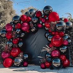 a large red and black balloon arch in the middle of a sidewalk