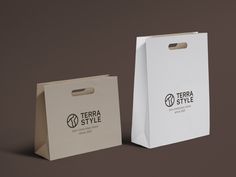 two white paper bags sitting next to each other on a brown surface with the words terra style printed on them