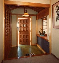 an entry way with a wooden door and plant on the shelf next to the entrance