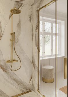 a bathroom with marble walls and flooring, gold fixtures on the shower head is shown