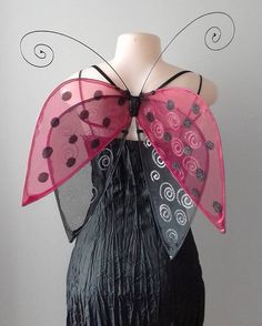 a mannequin dressed in black and pink with polka dots on it's wings