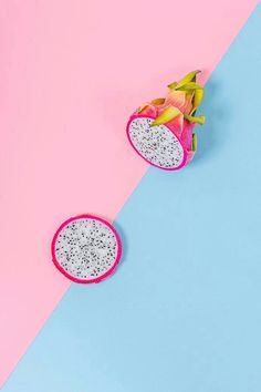 two pieces of dragon fruit on a pink and blue background with one cut in half