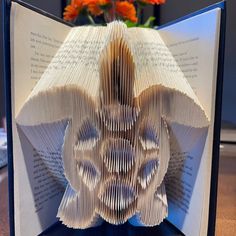 an open book with folded pages in the shape of a flower on top of it