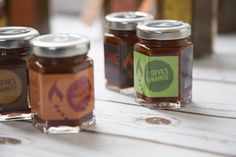 three jars of jam sitting on top of a wooden table