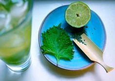 a blue plate topped with a green leaf next to a glass filled with water and lime