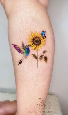 a sunflower with two hummingbirds on it's side and a blue butterfly sitting on top of the flower