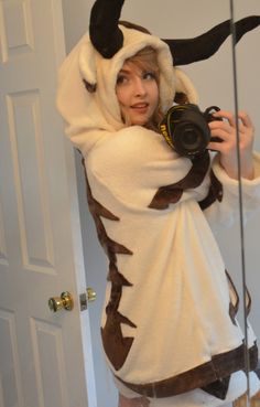 a woman in a costume taking a selfie with a camera while wearing a cow outfit