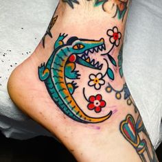 the foot is decorated with colorful tattoos and flowers on it's side, along with a dragon