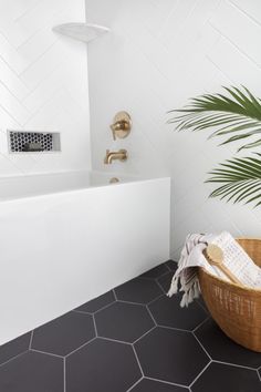 a bathroom with black and white tile flooring next to a plant in a basket