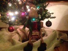 a stuffed animal under a christmas tree with lights on it's head and feet