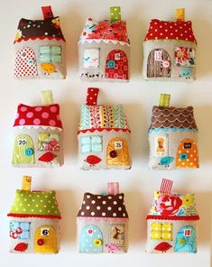 a group of small houses made out of different types of fabric on a white wall