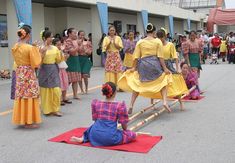 a group of women in colorful dresses standing on top of a red mat next to each other