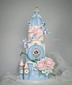 a three tiered cake with pink flowers and blue decorations